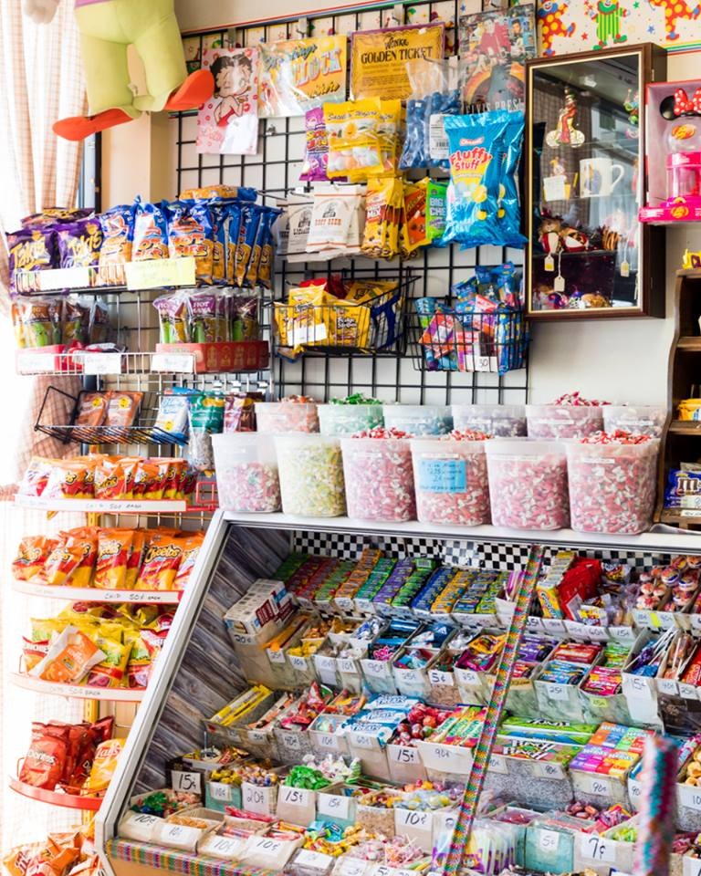 The candy wall in the shop: pegboard racks of snacks, tubs of loose candy and a glass case of penny sweets