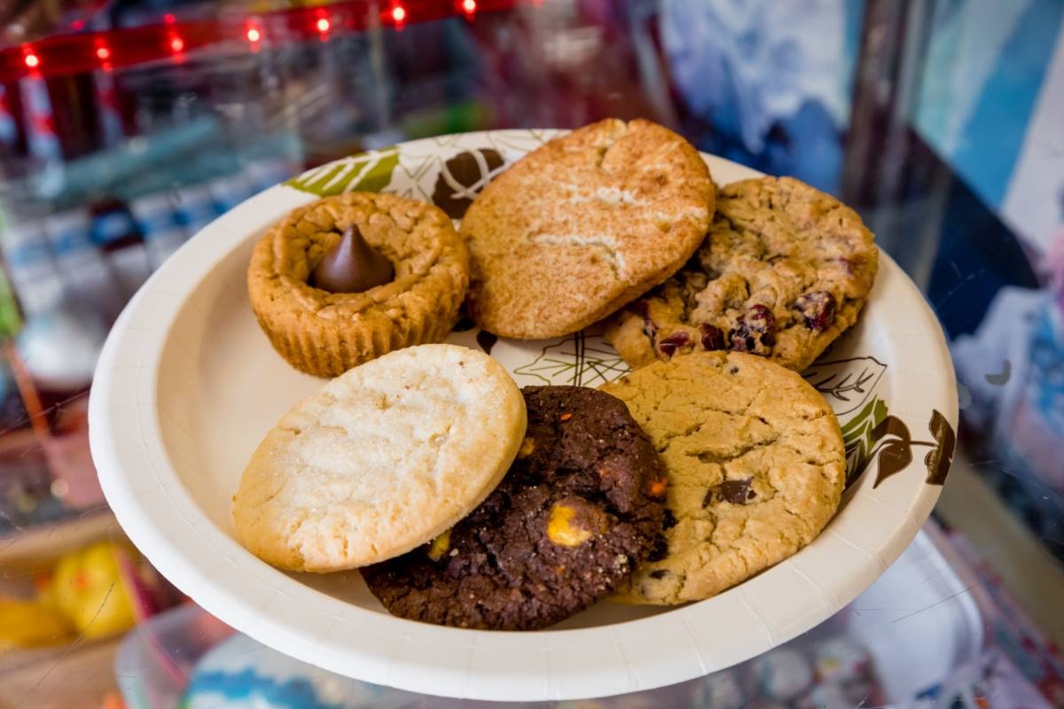 A plate of fresh cookies in the shop display case — snickerdoodle, chocolate chip, peanut butter blossom and more
