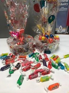 Candy buckets wrapped in cellophane and tied with ribbon, surrounded by loose wrapped candy